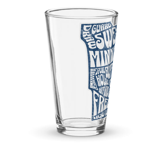 Side view of a clear shaker pint glass featuring a blue Minnesota state outline filled with curling terms such as sweep, guard, button, house, freeze, and hog line. Curling-themed drinkware by CRL.
