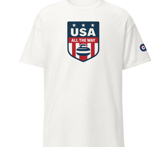 White unisex T-shirt with “USA All The Way” patriotic curling shield logo (red, white, blue) on front and curling target emblem on left sleeve.