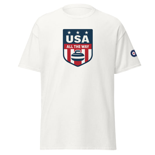 White unisex T-shirt with “USA All The Way” patriotic curling shield logo (red, white, blue) on front and curling target emblem on left sleeve.